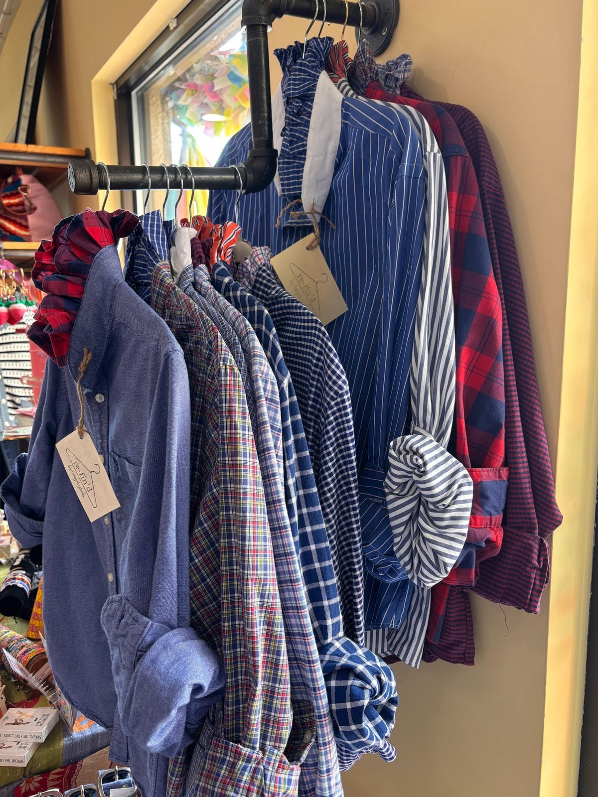 Collection of shirts hanging on a rack with tags, displayed in a store setting.