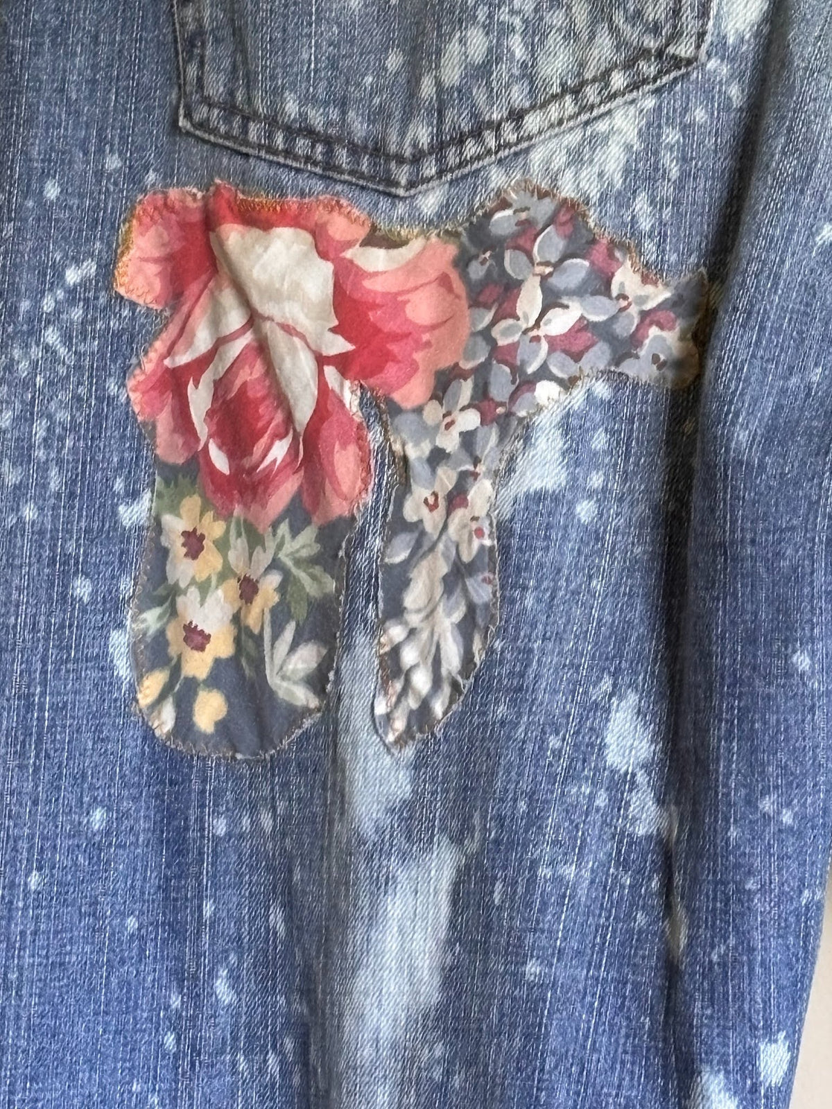 Denim jacket with floral patch on a light background