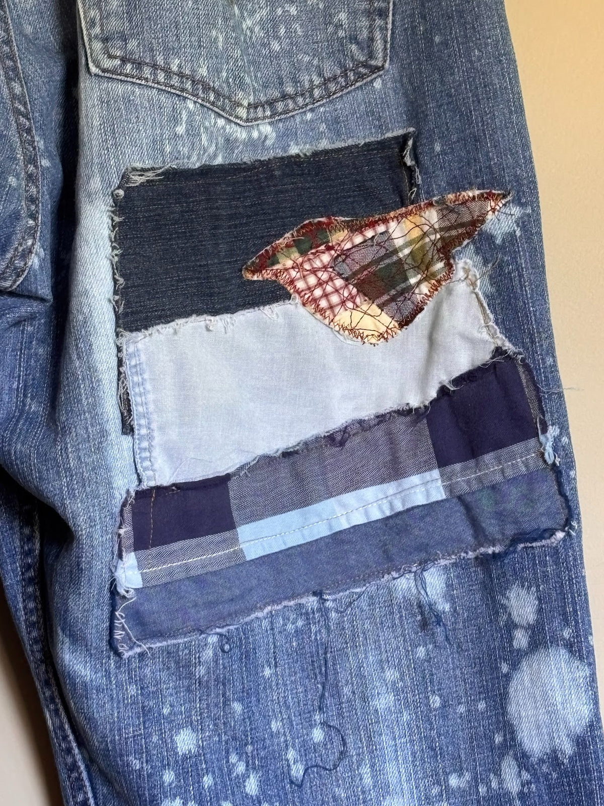 Close-up of a patchwork pocket on a denim jacket with a butterfly design.